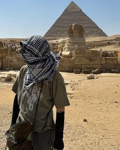 a man standing in front of the pyramids with his back turned to the camera