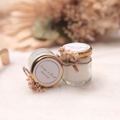 two small jars with labels on them are sitting next to some dried flowers and other items