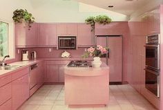 a kitchen with pink cabinets and white tile flooring is pictured in this image, there are two vases on the island