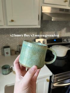 a person holding up a green mug in their hand with the words x2 honey fixx3 maybe green tea on it