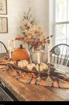 a wooden table topped with candles and pumpkins