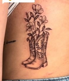 a tattoo with boots and flowers on the side of a woman's stomach,