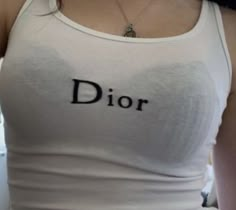 a woman wearing a white tank top with the word dior written in black on it