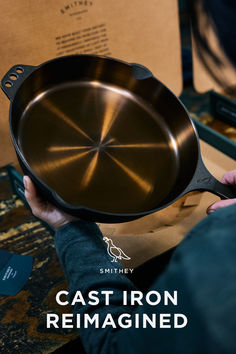 the cast iron remagined skillet is being held by someone's hand