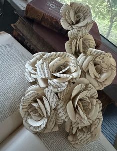 some books are stacked on top of each other with flowers made out of old book pages