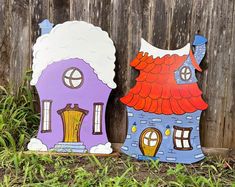 two wooden houses sitting next to each other on the ground in front of a fence