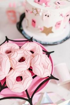 a pink plate topped with donuts on top of a table next to a cake