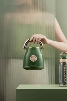 a green tea kettle being held by a woman's hand with an empty can next to it