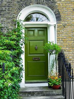 a green front door with potted plants on the steps