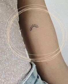 a woman's arm with a small sun tattoo on the left side of her arm