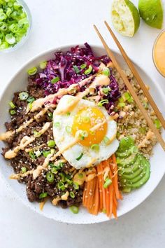 a white plate topped with rice, meat and veggies next to chopsticks