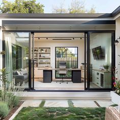 a modern home office with glass walls and sliding doors that open up to the backyard