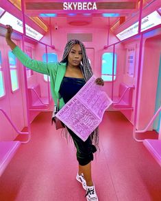 a woman is standing in a pink train car with her arms out and holding a large object