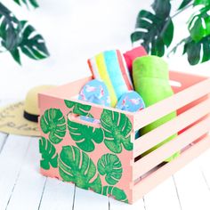 a wooden crate filled with towels and slippers on top of a white table next to a potted plant