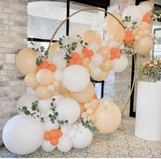 an arrangement of balloons and greenery in front of a brick wall