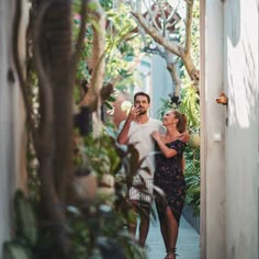 a man and woman are walking down the street talking on their cell phones