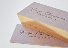 two business cards sitting on top of each other, one has a wooden handle and the other has a logo