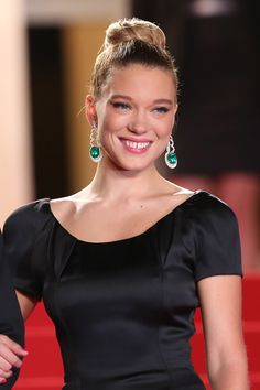 a woman in a black dress smiles at the camera while standing on a red carpet