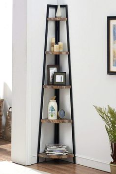 a corner shelf in the corner of a room with pictures on it and a potted plant next to it