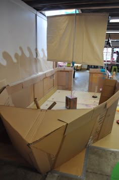 an open cardboard boat sitting on top of a table next to boxes and other items