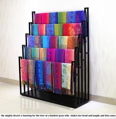 a rack with many colorful towels hanging from it's sides in front of a wall