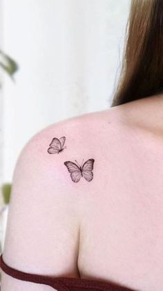 the back of a woman's shoulder with two butterflies on it