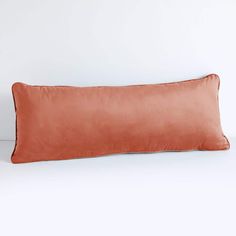 an orange pillow sitting on top of a white table