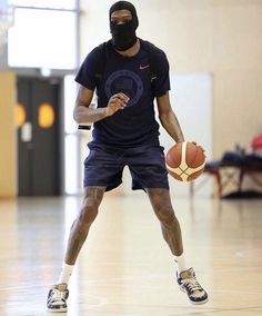 a man holding a basketball while wearing a face mask