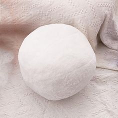 a white round object sitting on top of a bed next to a pink and white blanket