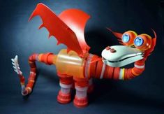 an orange and white toy dragon with blue eyes on it's head, standing in front of a black background