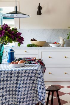 a kitchen with a checkered table cloth and blue vases filled with purple flowers