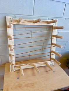 a wooden frame with several pegs attached to it on top of a table next to a potted plant