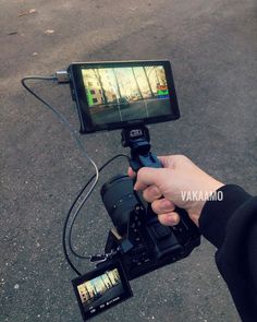 a person holding a camera with a video attached to it's handle and recording the scene