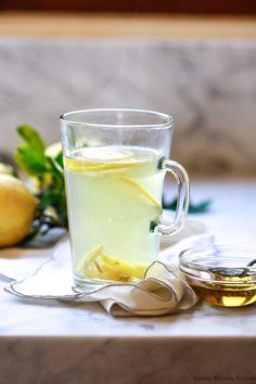 a glass cup filled with liquid next to sliced lemons