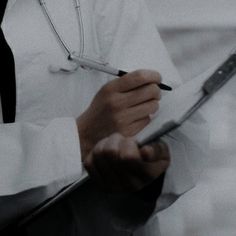 a man in a white shirt and tie writing on a piece of paper with a stethoscope