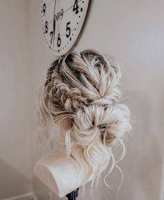 a woman's hair is braided into a bun in front of a clock