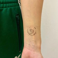 a woman's arm with a small cactus tattoo on the left side of her wrist