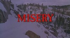 the title for misery is displayed in front of a snowy mountain with trees and rocks