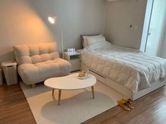 a bed room with a neatly made bed next to a white couch and coffee table