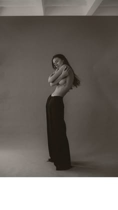 black and white photograph of woman in long dress with arms folded over her chest, looking down