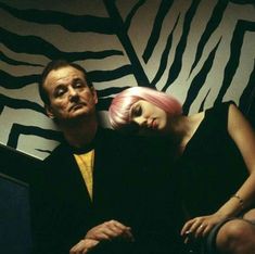 a man and woman sitting next to each other in front of a zebra print wall