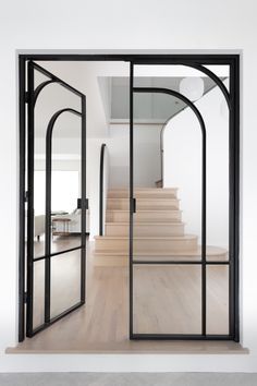 an open door leading into a white room with wooden floors and glass doors that lead to the second floor