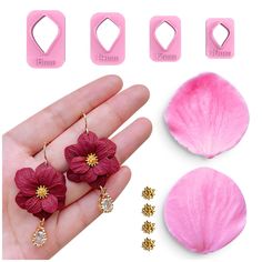 the pink flower earrings are being held up by someone's hand and other accessories