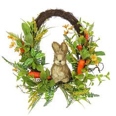 a rabbit sitting in the middle of a wreath with carrots and ferns on it