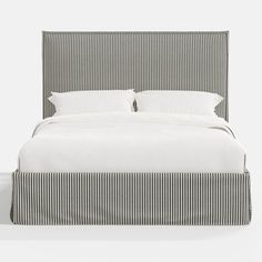 an upholstered bed with white linens and black pinstripe print on the headboard