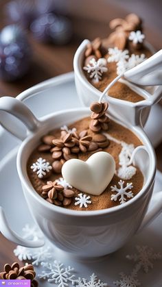 two white bowls filled with hot chocolate and topped with marshmallows, snowflakes and hearts