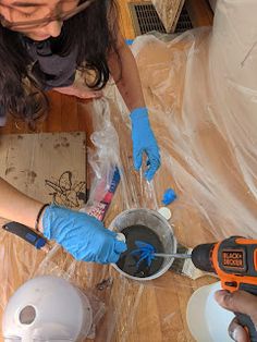 two people in blue gloves are working on some construction materials with tools and plastic wrap around them