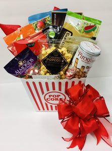 a popcorn box filled with lots of snacks and candy, along with a red bow