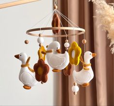 a mobile with ducks hanging from it's sides in front of a drapes