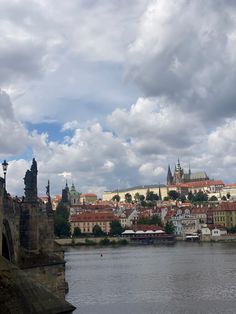 the view of prague from across the river on a cloudy day with clouds in the sky